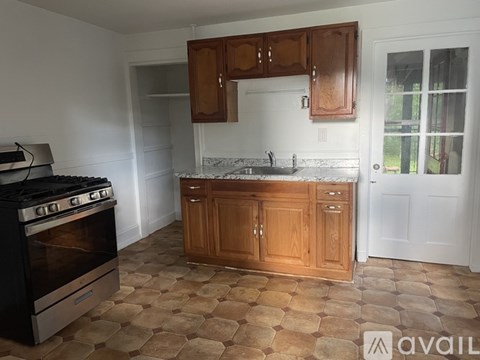 A kitchen with a black stove top oven and wooden cabinets.