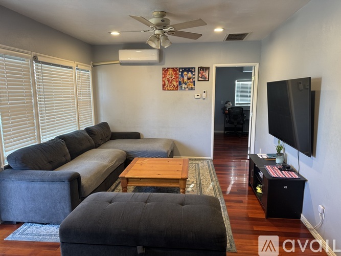 A living room with a grey couch, a wooden coffee table, and a flat screen TV mounted on the wall.