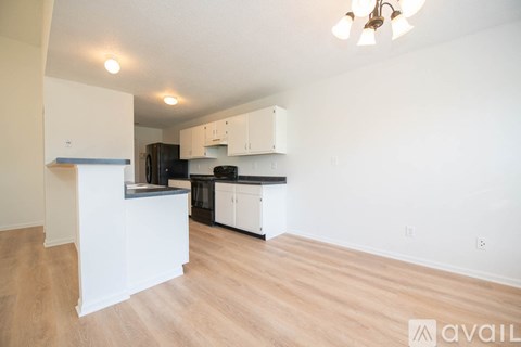 A kitchen with white cabinets and a wooden floor.