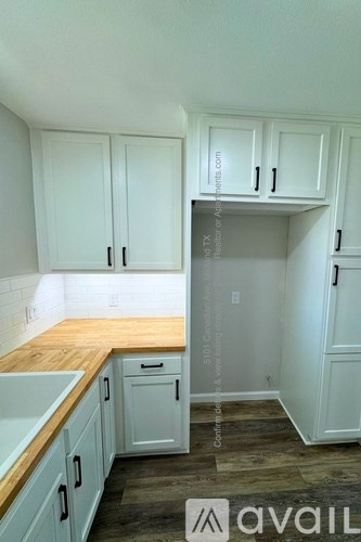A kitchen with white cabinets and a wooden counter top.