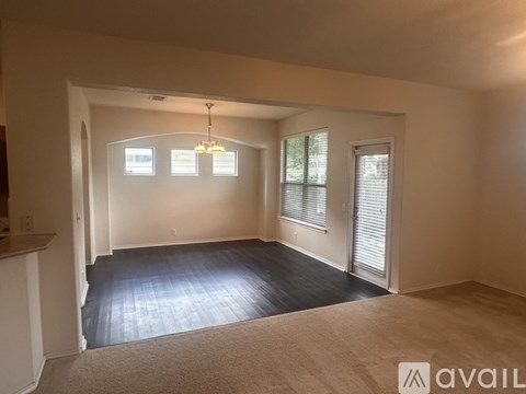 A spacious room with a carpeted floor and a chandelier hanging from the ceiling.