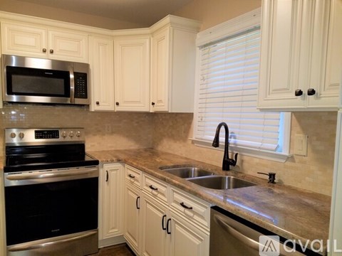 A kitchen with white cabinets and a black stove top oven.
