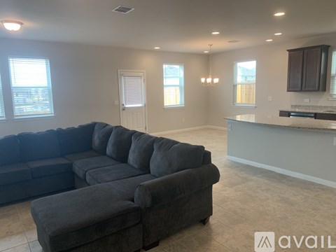A living room with a grey sectional sofa and a kitchen area in the background.