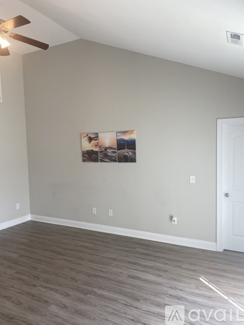 A room with a ceiling fan and a painting on the wall.