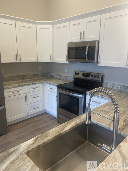 A kitchen with a stainless steel sink and white cabinets.
