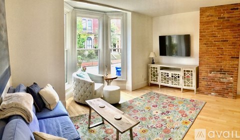 A living room with a blue couch and a television on a white cabinet.