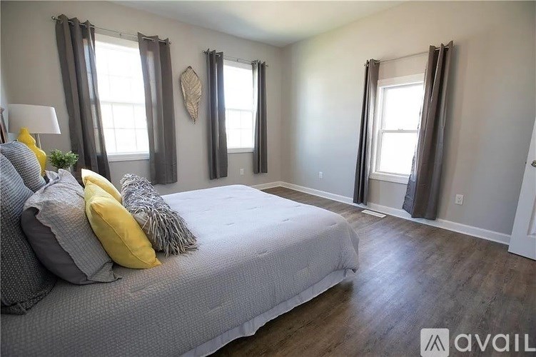 A bedroom with a large bed and two windows.