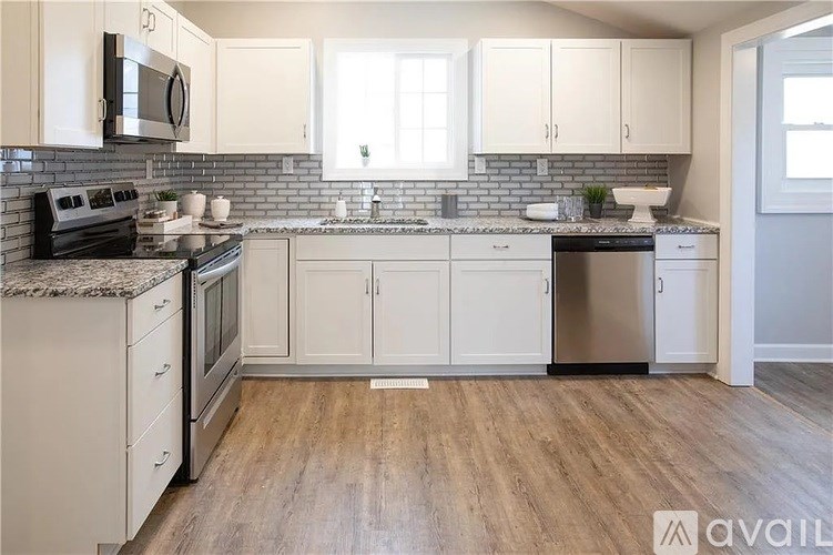 A kitchen with white cabinets and a wooden floor.