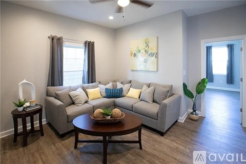 A living room with a grey couch, a brown table, and a painting on the wall.