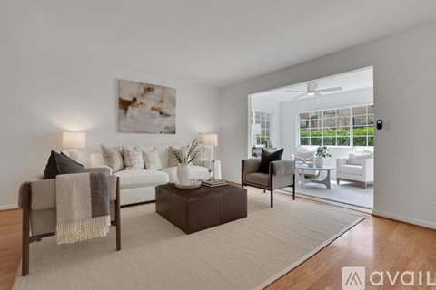 A living room with a white couch, a brown coffee table, and a painting on the wall.