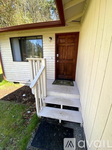 A small house with a brown door and a white porch.