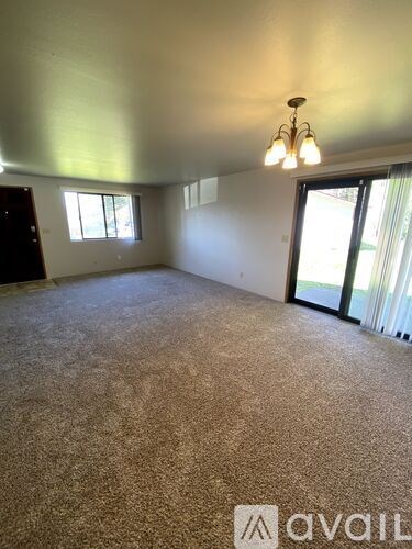 A room with a carpeted floor and a chandelier hanging from the ceiling.