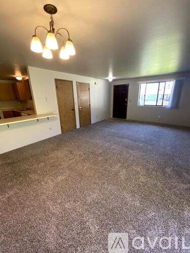 A room with a carpeted floor and a chandelier hanging from the ceiling.