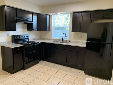 A kitchen with black cabinets and appliances.