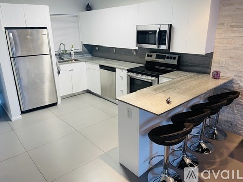 A kitchen with white cabinets and a stainless steel refrigerator.