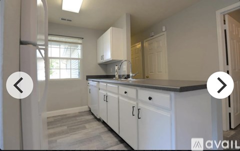 A kitchen with white cabinets and a black countertop.