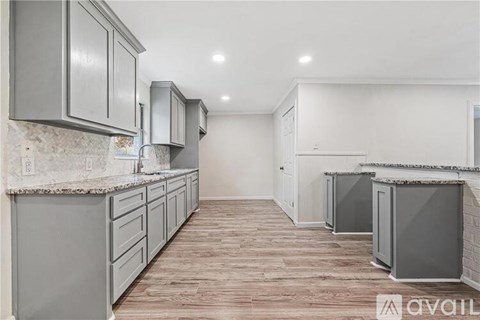 A kitchen with grey cabinets and a wooden floor.