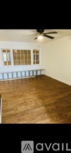 A room with a ceiling fan and wooden flooring.