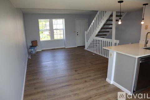 A kitchen with a white counter and a staircase in the background.