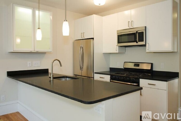 A kitchen with white cabinets and a black countertop.
