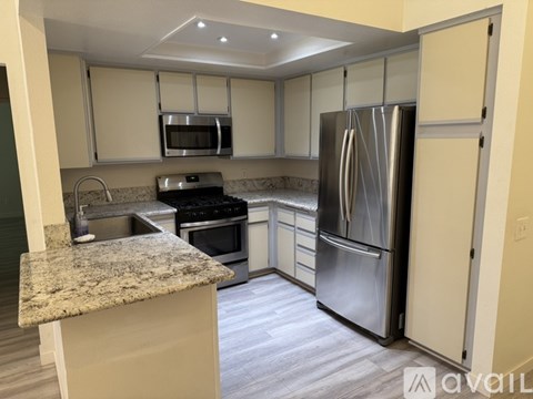 A kitchen with a granite countertop and stainless steel appliances.