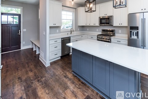A kitchen with white countertops and dark wood floors.