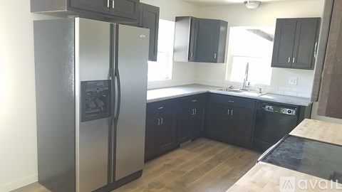 A kitchen with a stainless steel refrigerator and black cabinets.