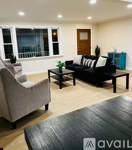 A living room with a grey couch, a black sofa, a wooden table, and a grey armchair.