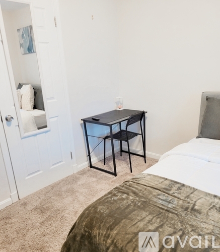 A bedroom with a bed, a table with two chairs, and a door.