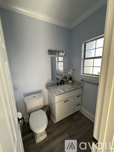A bathroom with a toilet, sink, and a window.