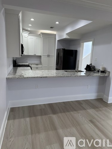 A kitchen with a granite countertop and wooden flooring.