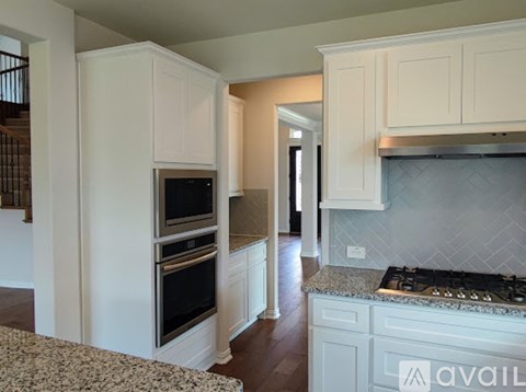 A kitchen with white cabinets and a black stove top.