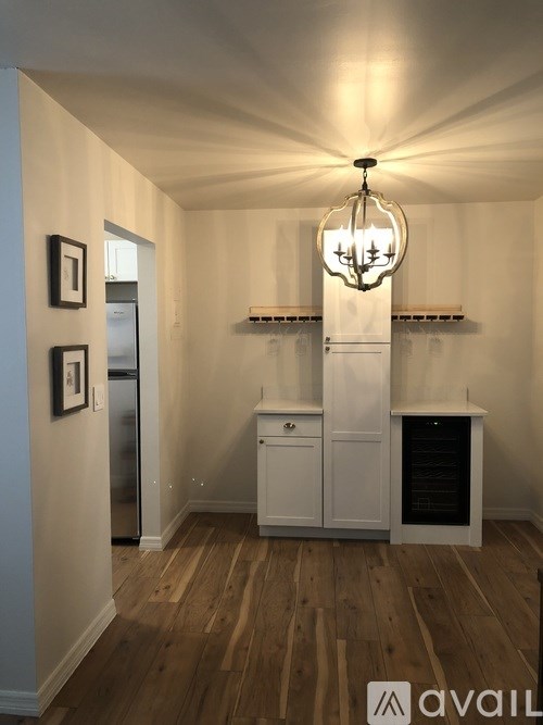 A kitchen with a chandelier, a fridge, a cabinet, and a wine rack.
