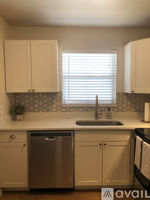 A kitchen with a stainless steel dishwasher and white cabinets.