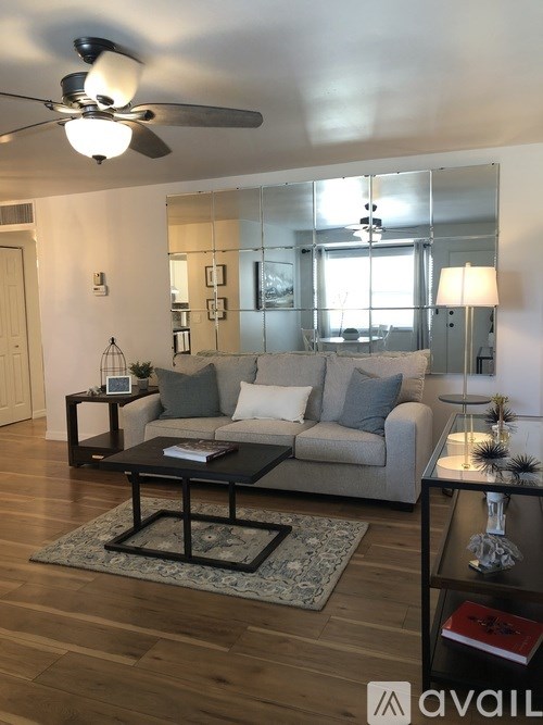 A living room with a grey couch, a black coffee table, and a ceiling fan.