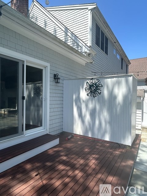 A house with a white exterior and a wooden deck.