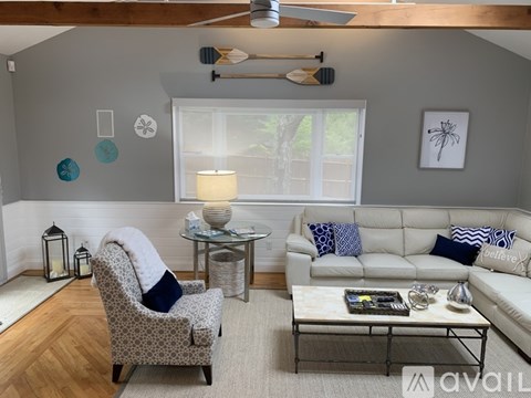 A living room with a white couch, a grey armchair, and a coffee table.