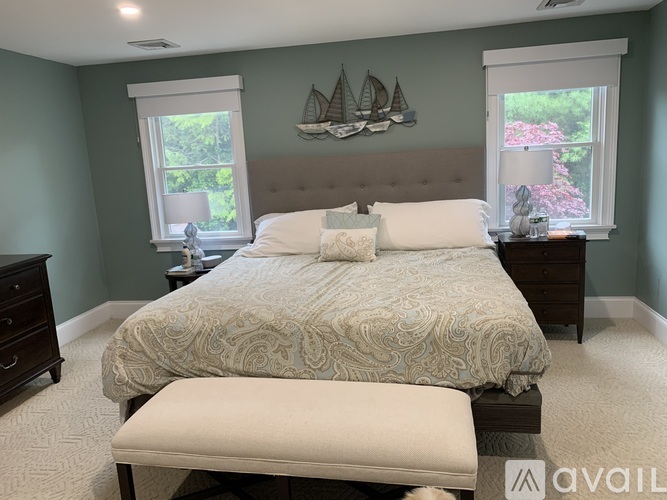 A bedroom with a large bed and a window with a view of a garden.