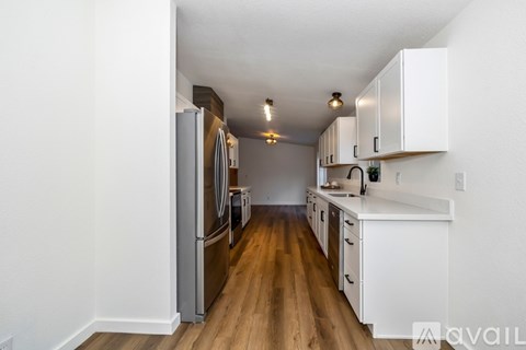 A kitchen with white cabinets and a wooden floor.