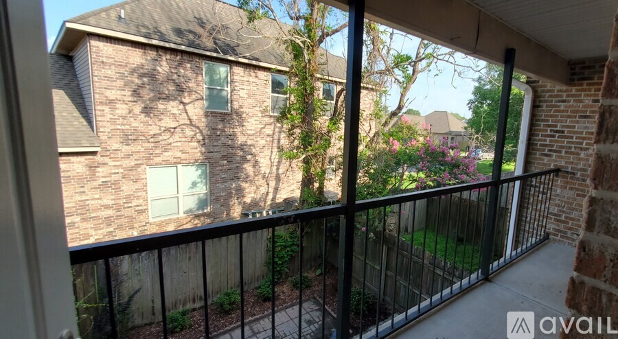 A balcony with a black railing and a brick building in the background.