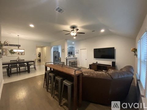 A living room with a brown couch and a television on the wall.