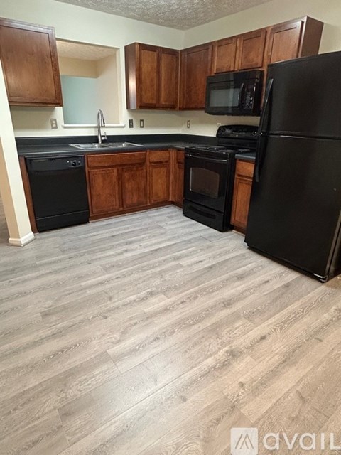 A kitchen with black appliances and wooden cabinets.