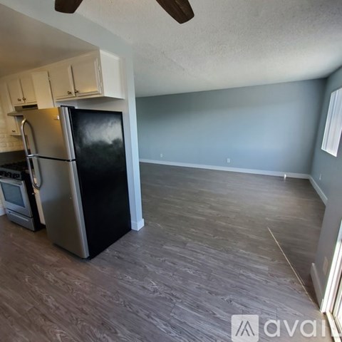 A kitchen with a black fridge and wooden floors.