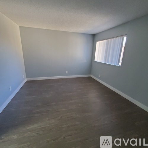 A room with wooden flooring and a window with blinds.
