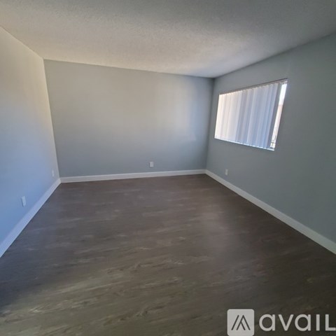 A room with wooden flooring and a window with blinds.