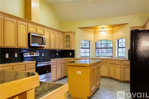 A kitchen with wooden cabinets and a black refrigerator.