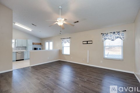 A spacious living room with wood flooring and a ceiling fan.