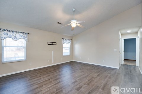 A spacious room with wooden flooring and a ceiling fan.