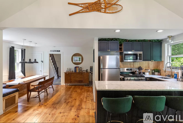 A kitchen with green chairs and a wooden floor.