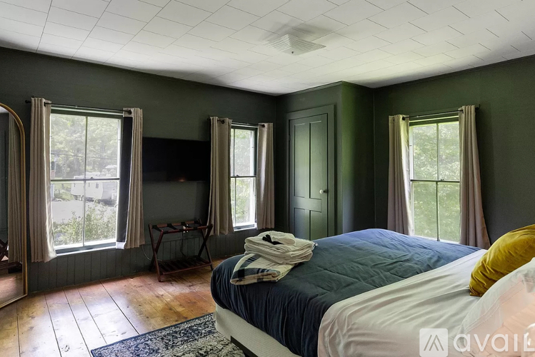 A bedroom with a bed, a chair, and a window.
